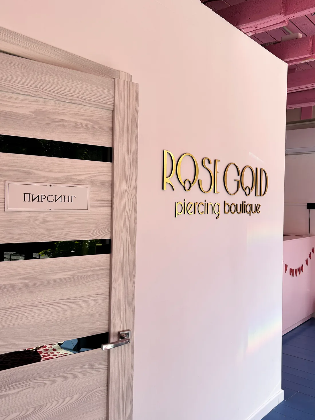 Вывеска Rose Gold piercing boutique рядом с дверью кабинета.